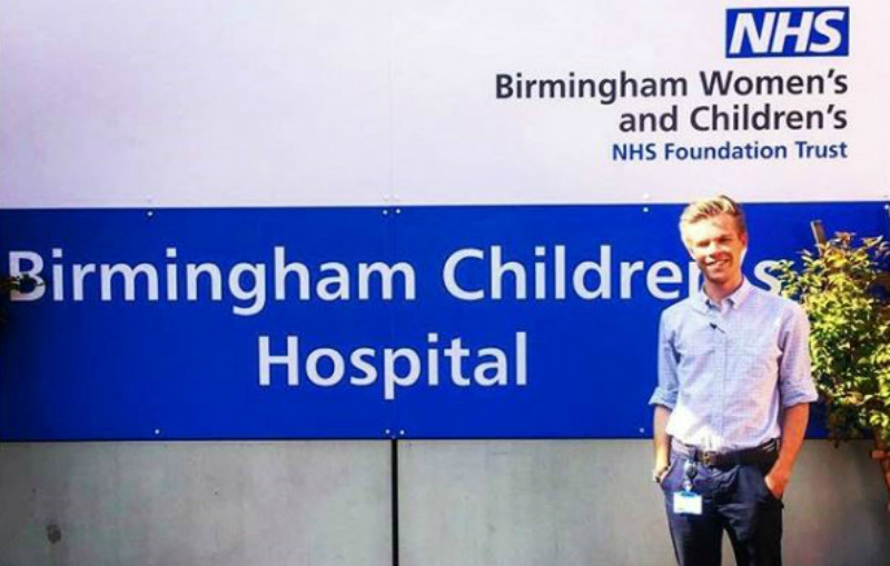 Josh Tulley stands in front of Birmingham Children's Hospital