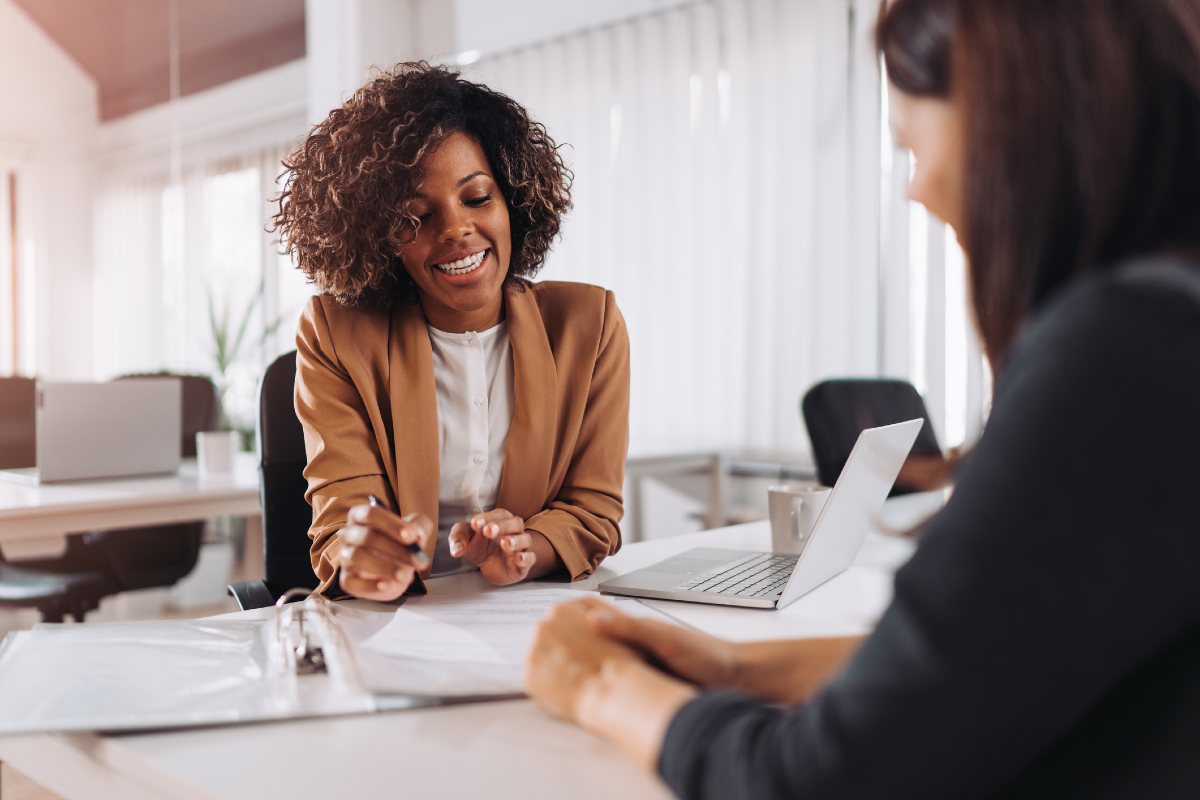 Professional woman in office with paperwork talking to customer Professional woman in office with paperwork talking to customer