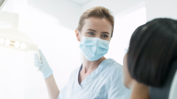 Female dentist wearing mask with patient in chair