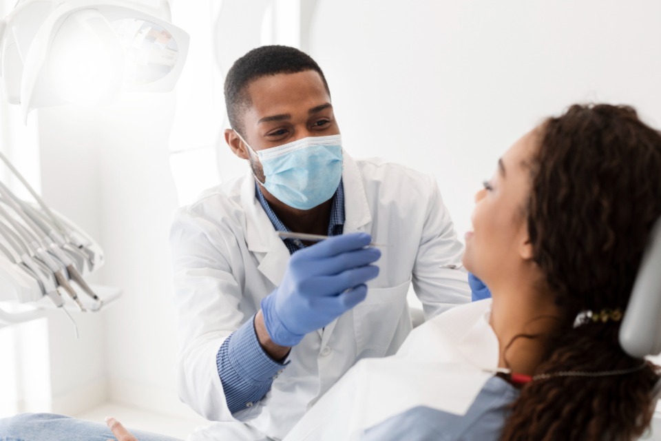 Dentist wearing mask and white coat treating patient