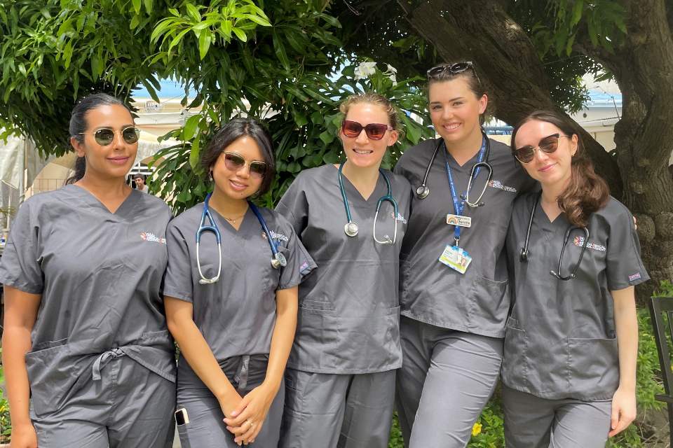 Charlotte Smith and other medical students in scrubs standing together on a beach in the Caribbean