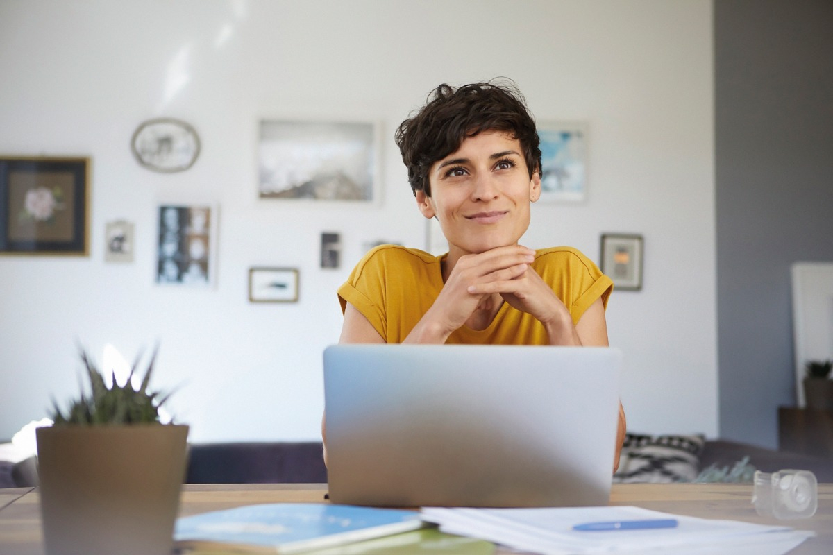 Smiling woman sitting at breakfast bar with laptop