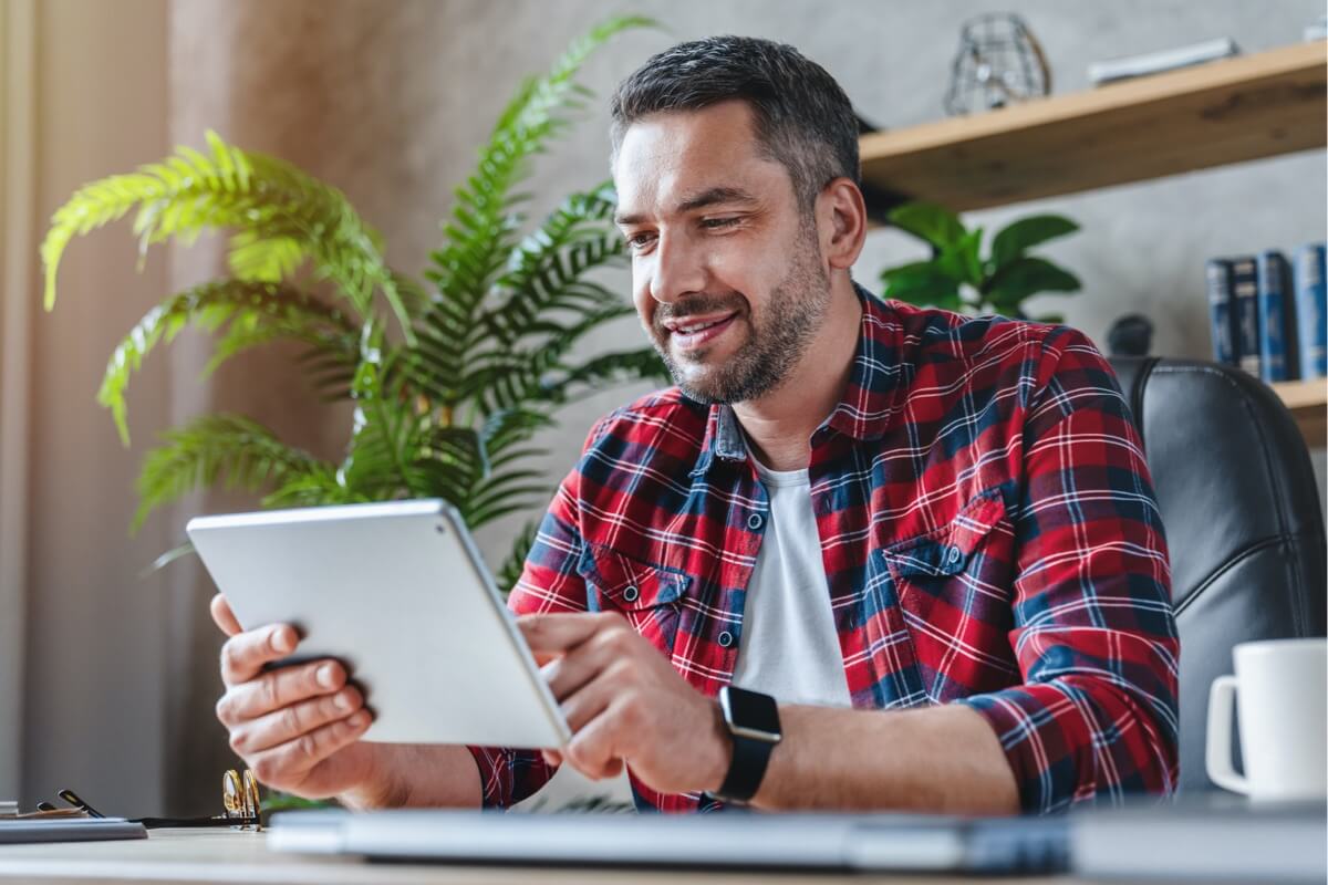 Man in checked shirt looking at tablet