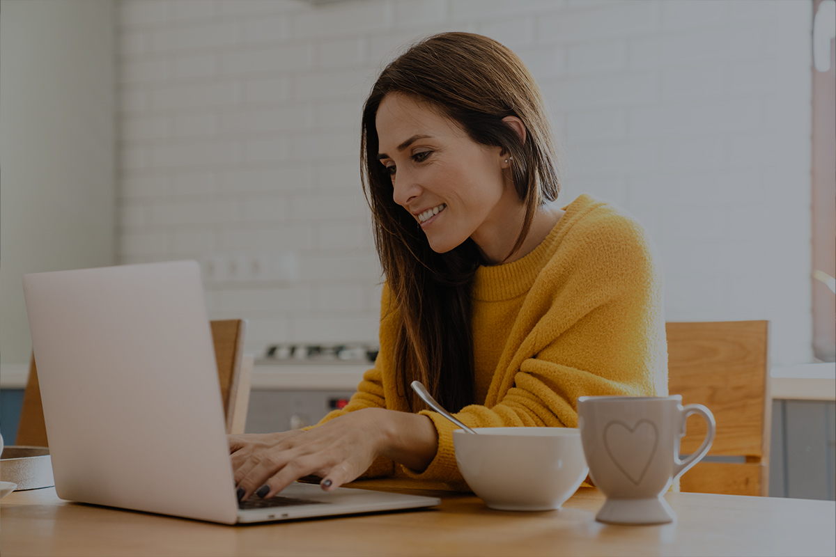 Woman sitting at kitchen table on laptop