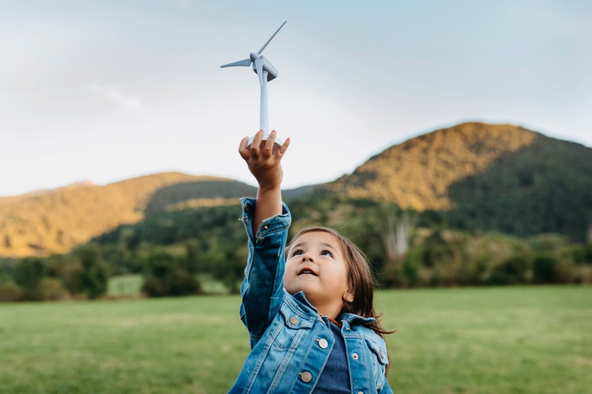 Young girl in the countryside holding up a toy windmill