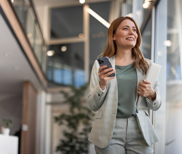 Female looking up and smiling and holding a phone and notebook