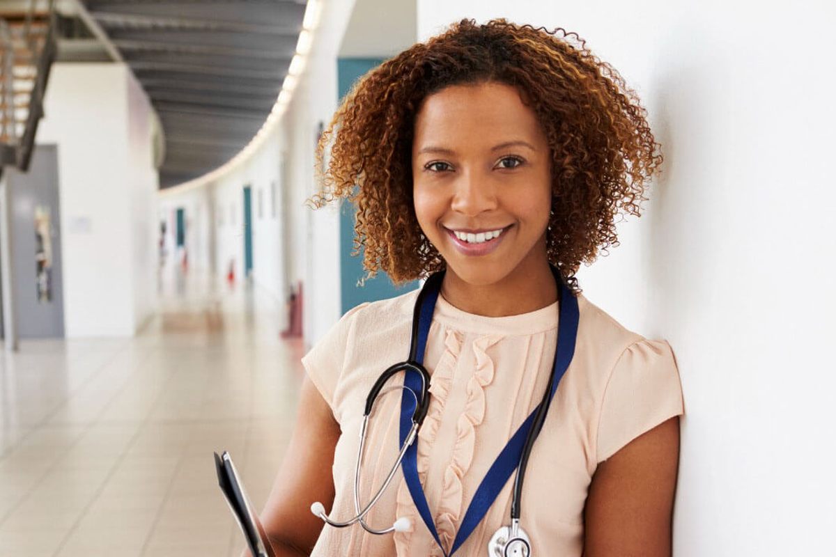 Female medic standing against wall holding clipboard