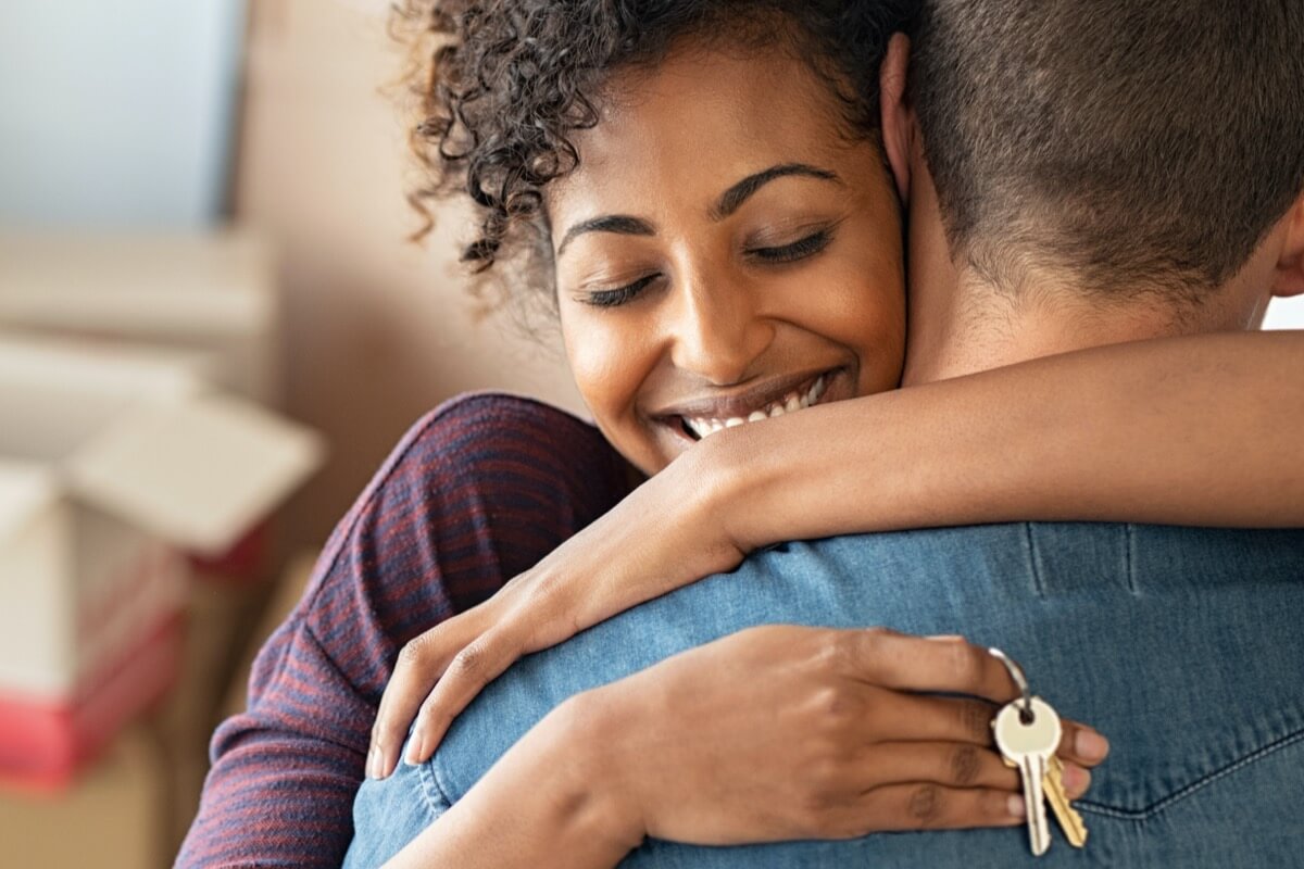 Happy woman hugging partner in new home