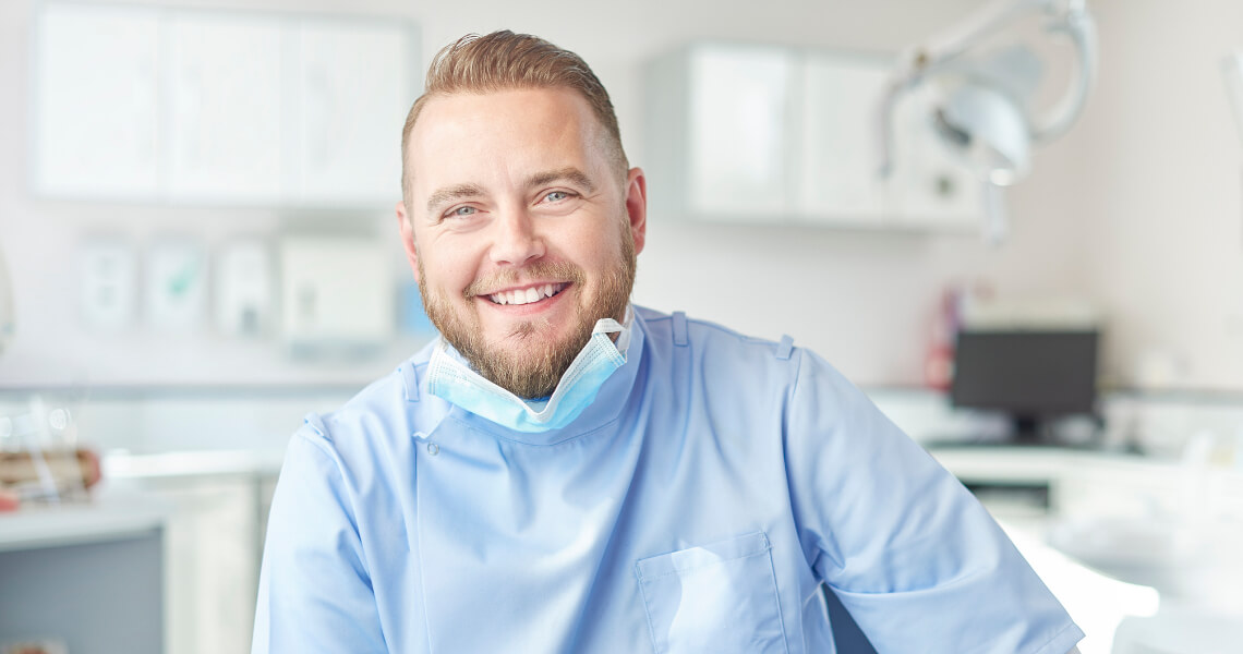 Male dentist in lowered face mask