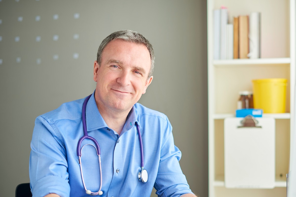 Male doctor in office with paperwork and pen