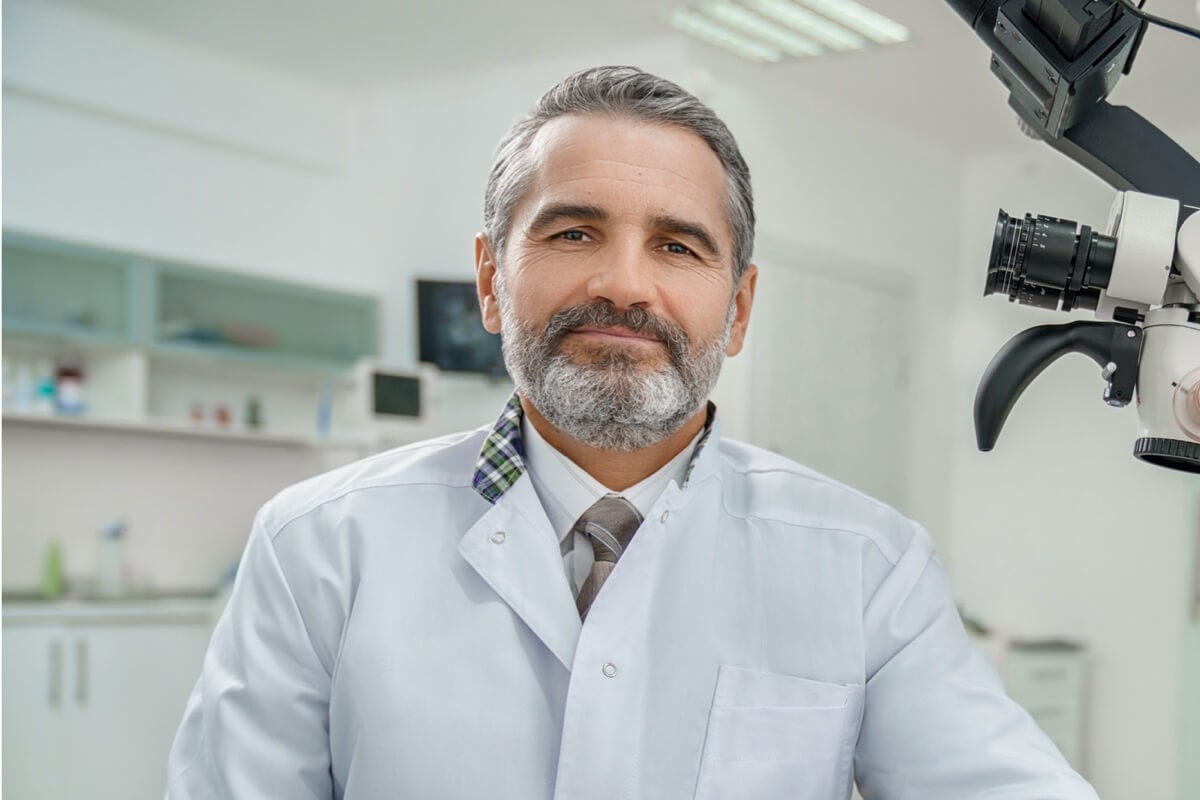 Mature male dentist wearing tie sitting on chair