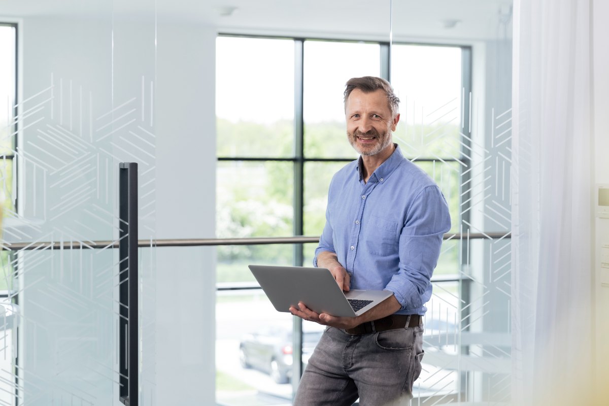 Professional man in office standing holding laptop