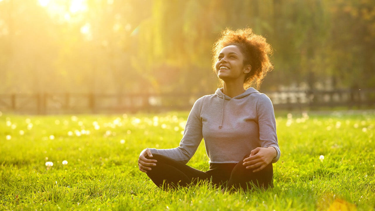 Woman sat on grass crossed legged smiling