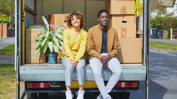 Couple sitting on edge of removal van