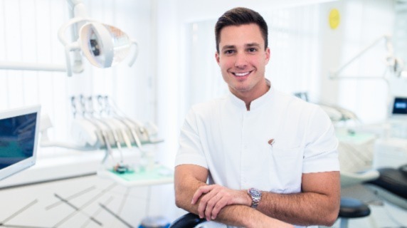 Male dentist smiling in examination room