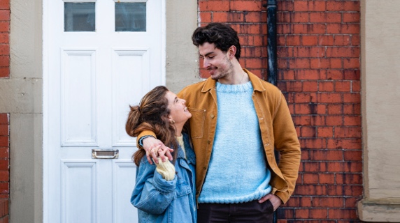 Young happy couple standing outside new home