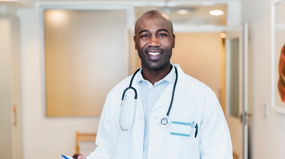 Male medical professional standing in corridor wearing white lab coat