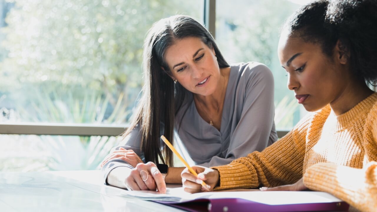 Mature female teacher sitting with student