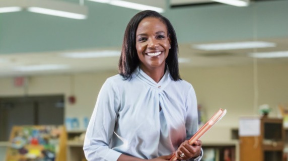 Female teacher holding books in classroom