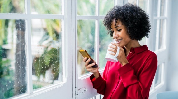 Woman standing in window holding mug and plane