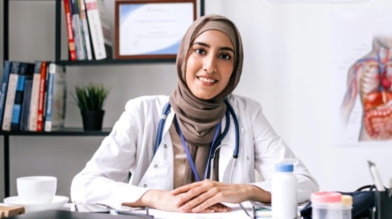 Female doctor wearing head scarf sitting at desk