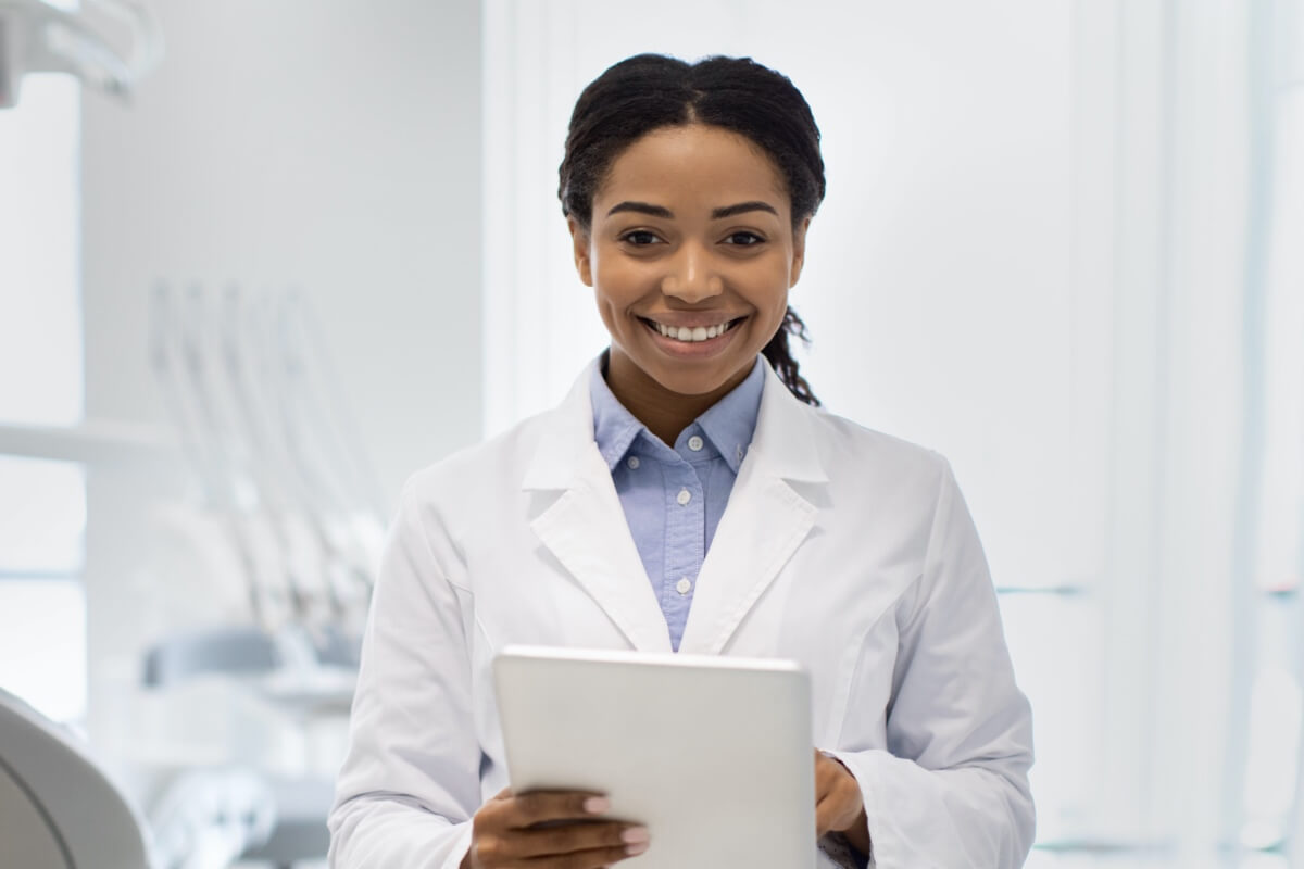 Happy young female dentist holding ipad