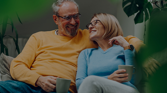 Retirement Club mature couple on sofa holding mugs