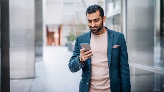 Smartly dressed Asian man smiling down at phone