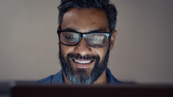 Smiling man in glasses looking at laptop