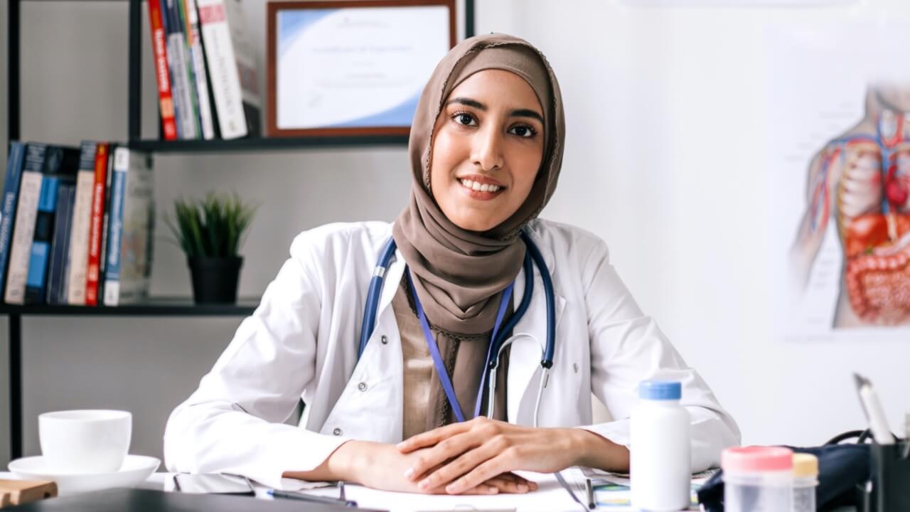 Female doctor wearing head scarf sitting at desk