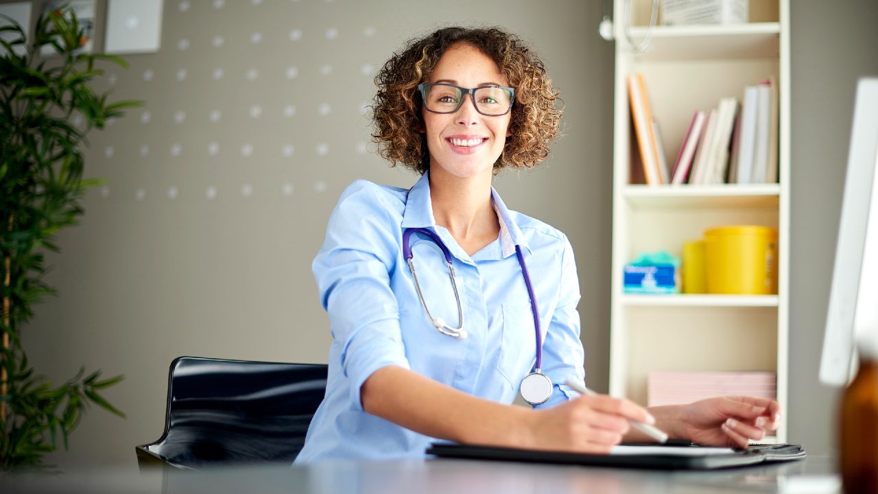 Female medical professional at desk holding pen