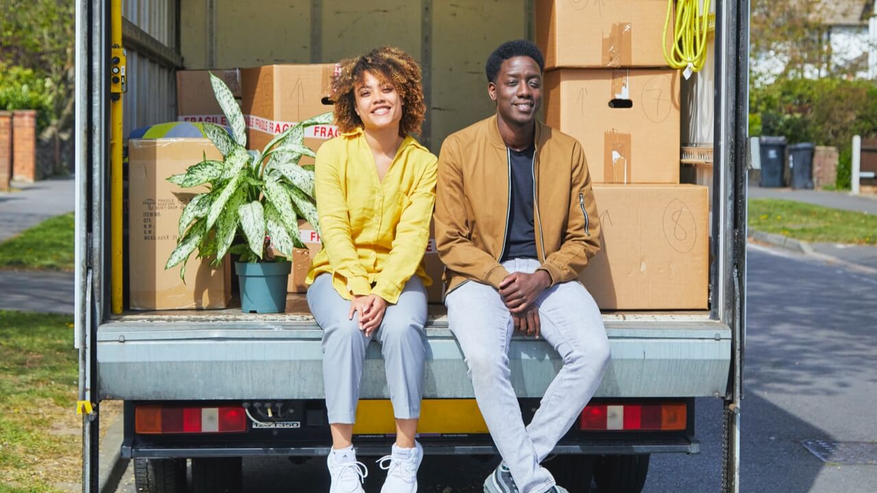 Couple sitting on edge of removal van