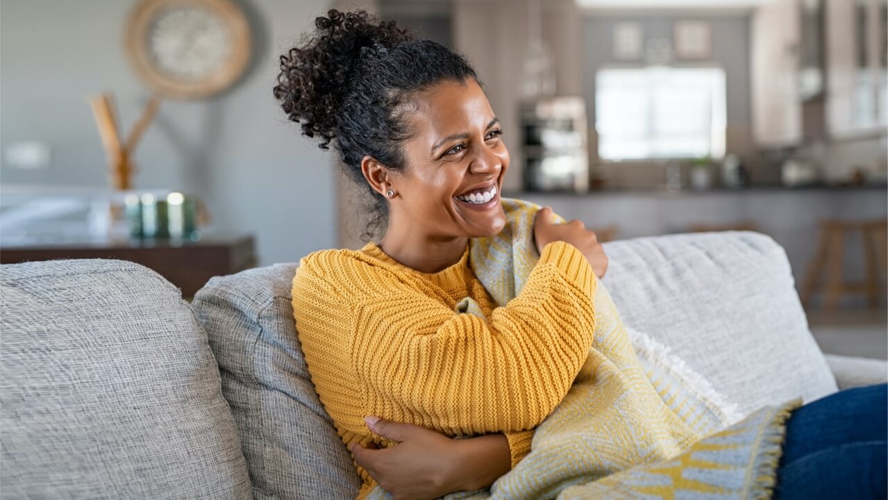 Happy female sitting on sofa in home