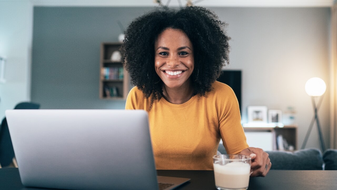 Woman smiling sitting at breakfast bar with laptop