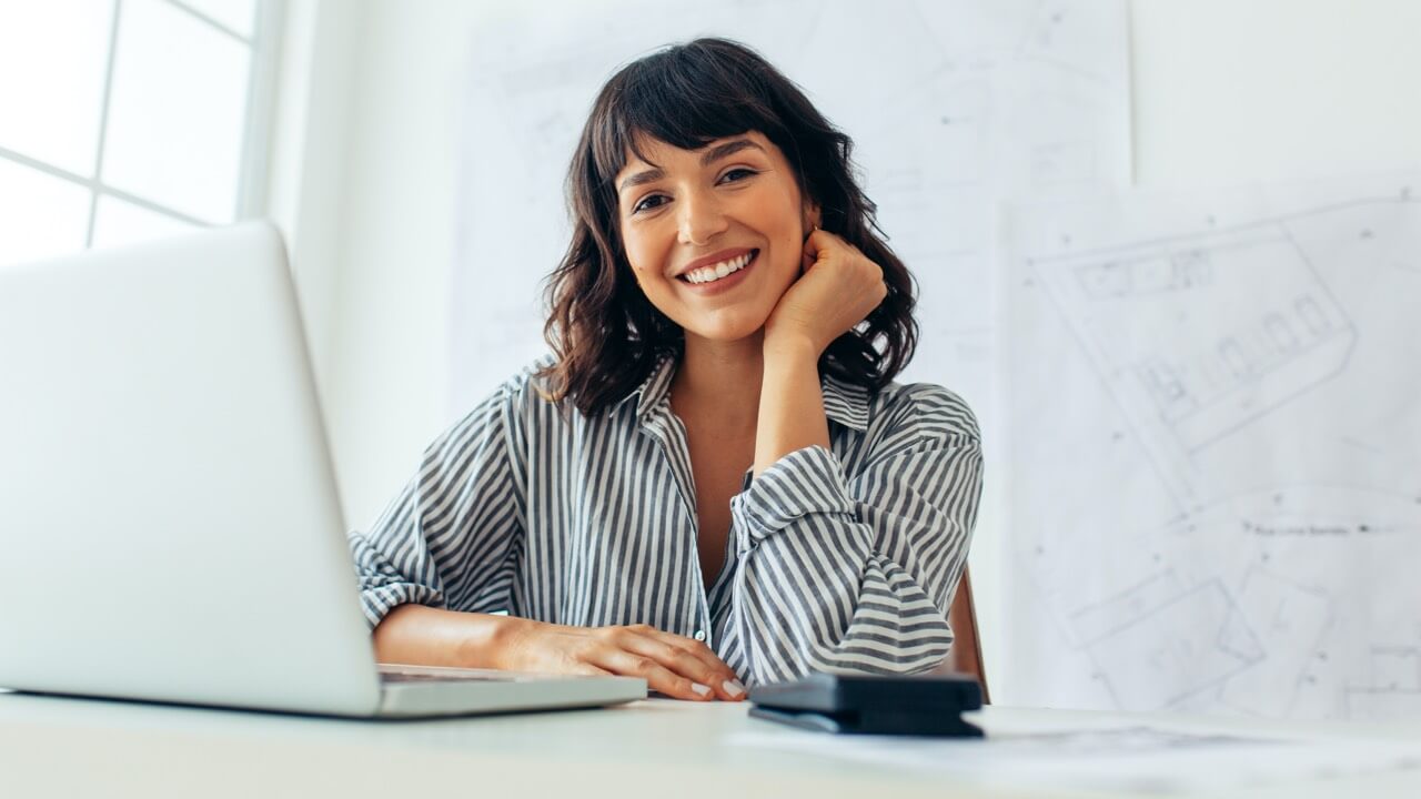 Young woman in a bright white office with an open laptop on desk