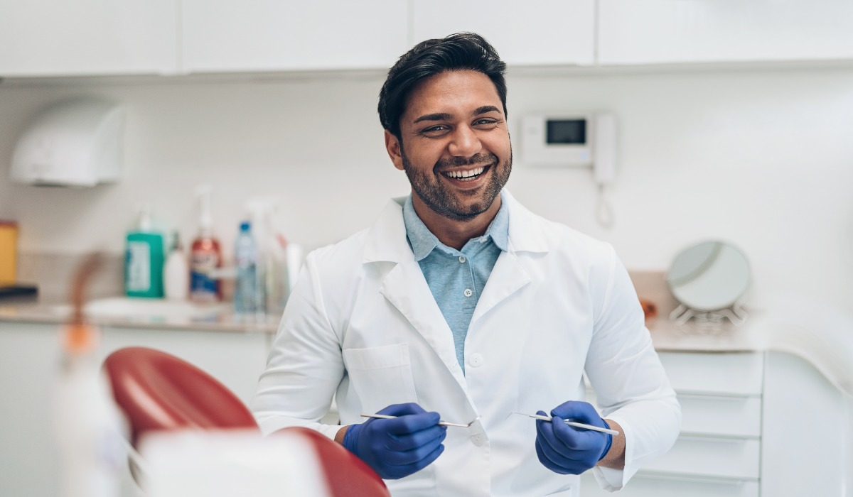 Male dentist holding equipment smiling