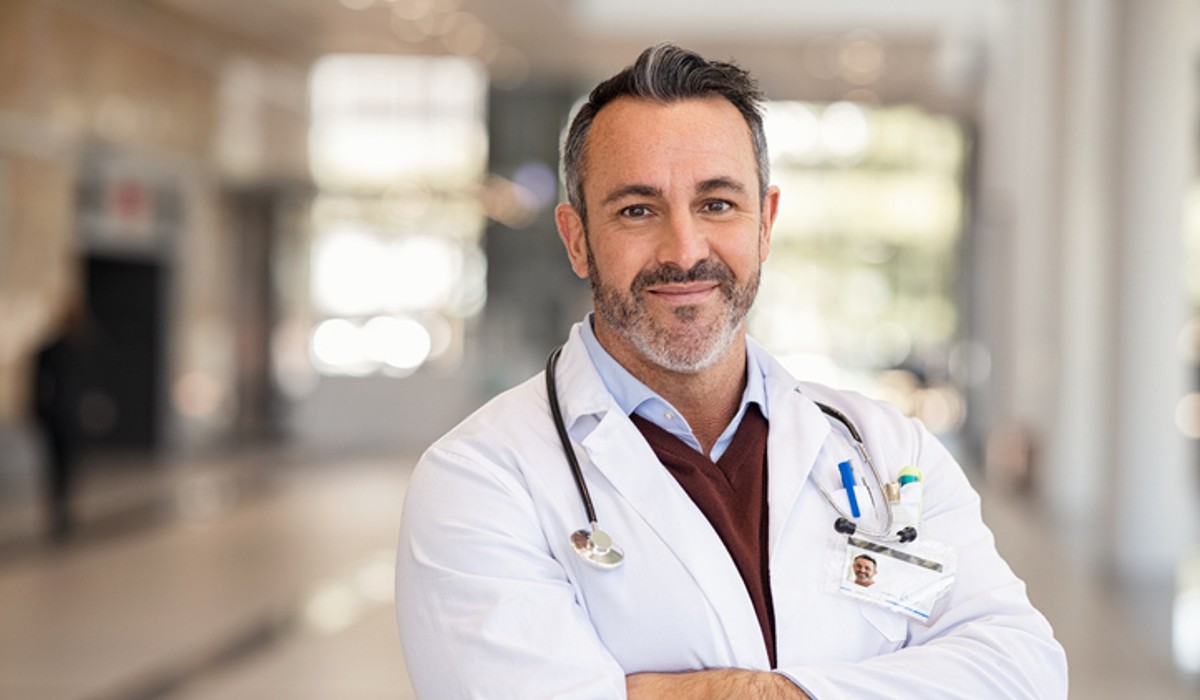 Male doctor standing in corridor with crossed arms