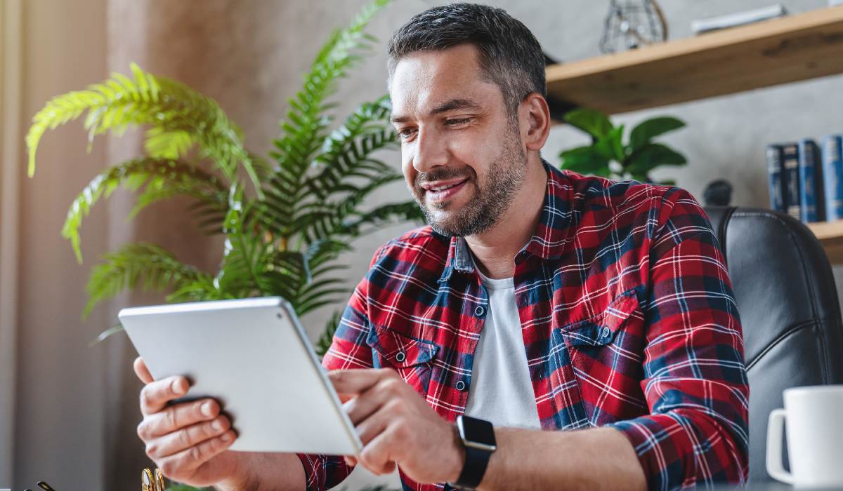 Man in office smiling at desk using tablet