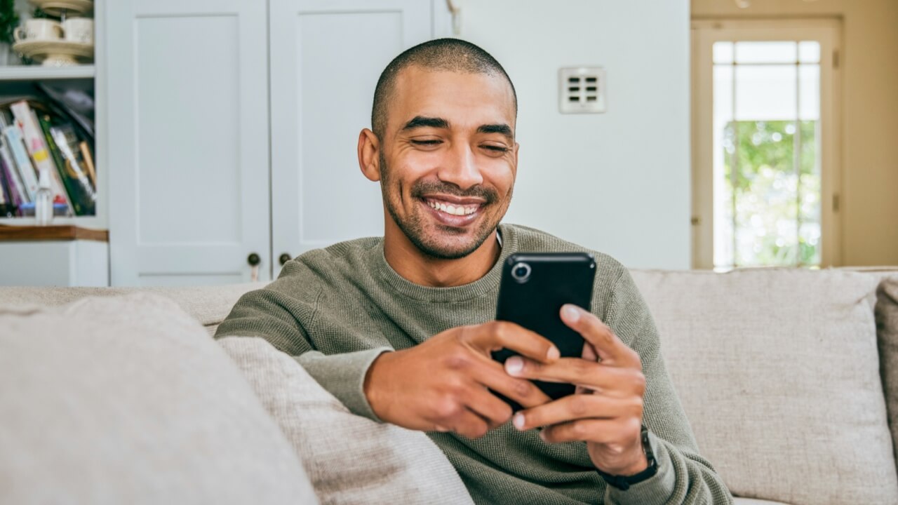 Man sitting in living room smiling at phone