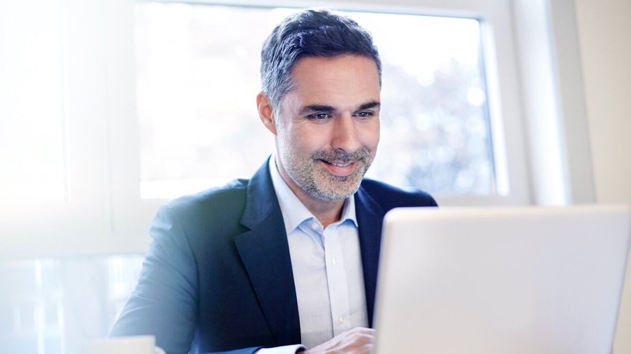 Mature businessman looking at laptop smiling