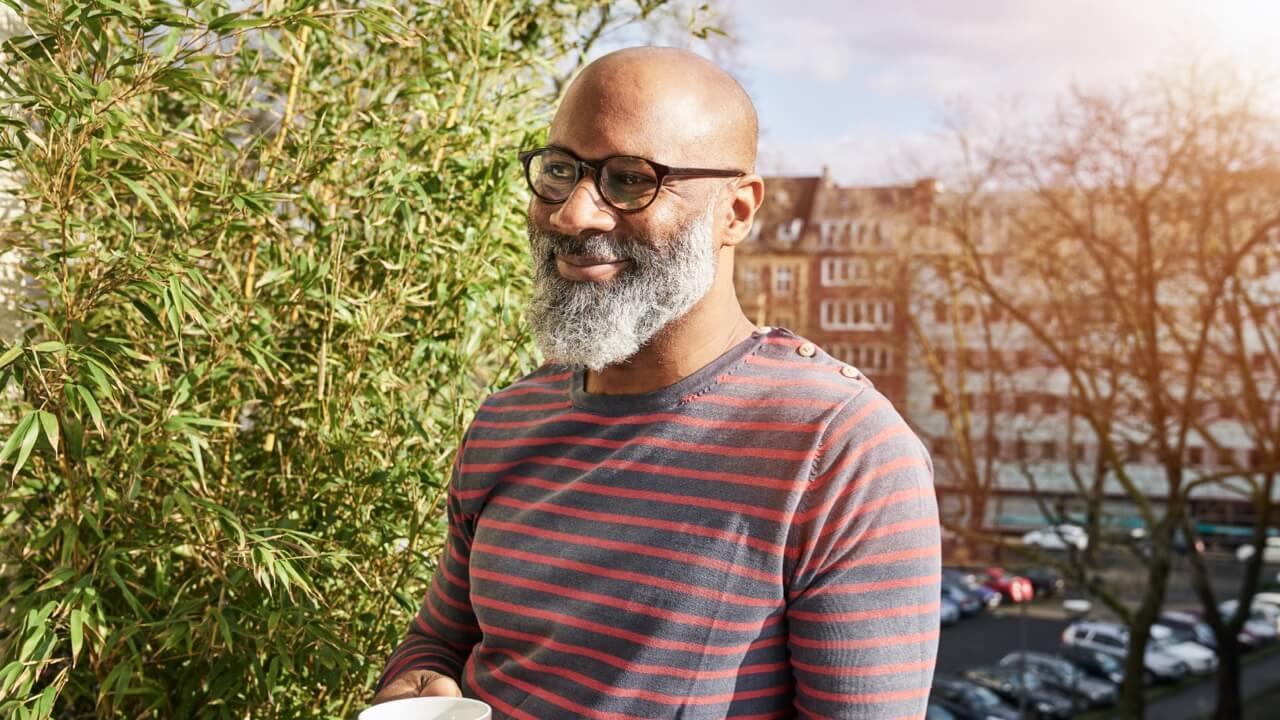 Mature man in glasses standing on balcony