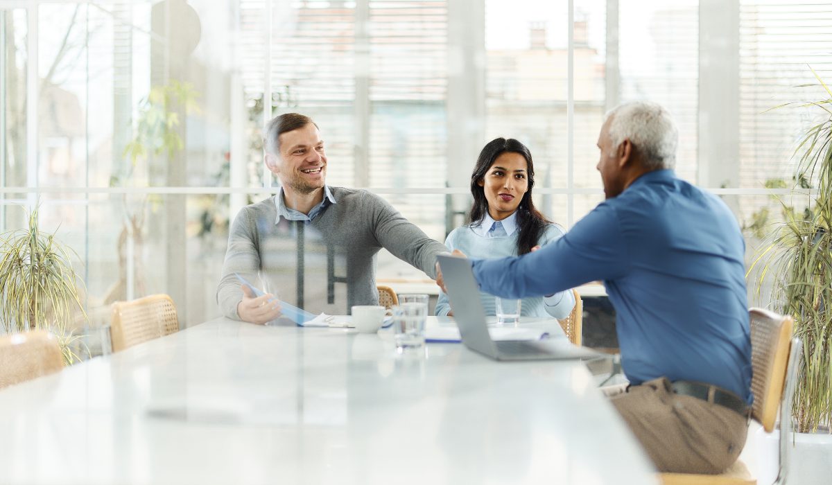 Three professionals in meeting room shaking hands