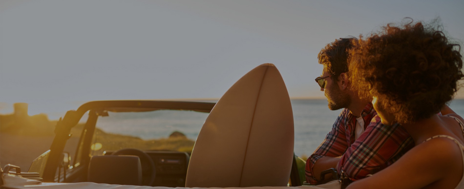 Young couple look out at sunset at beach