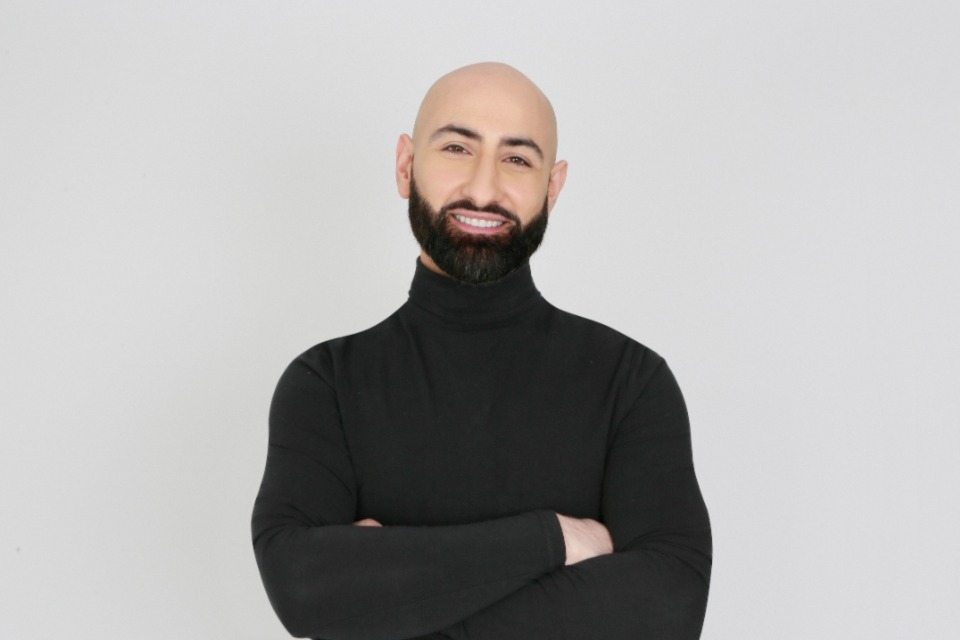 Dr Milad Shadrooh, the 'Singing Dentist', wearing a black turtleneck with crossed arms