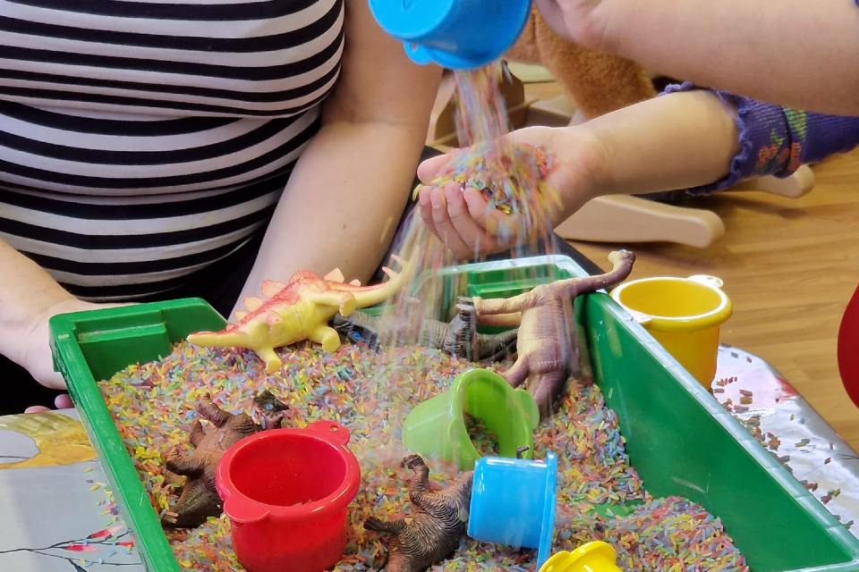 Child playing with coloured rice and toys