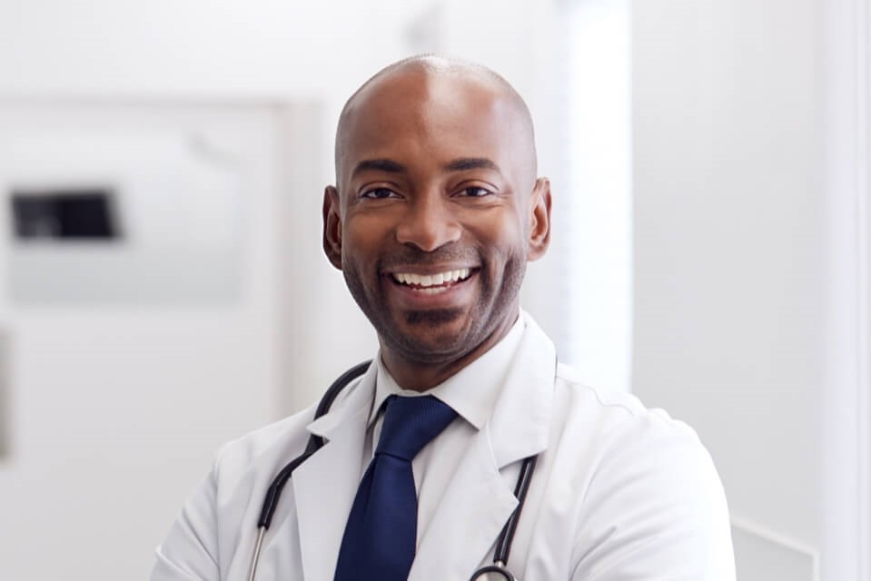 Mature male doctor smiling in GP corridor