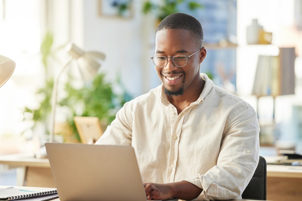 Professional man at desk using laptop smiling