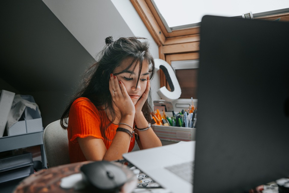 Student on home desk with chin resting on hands