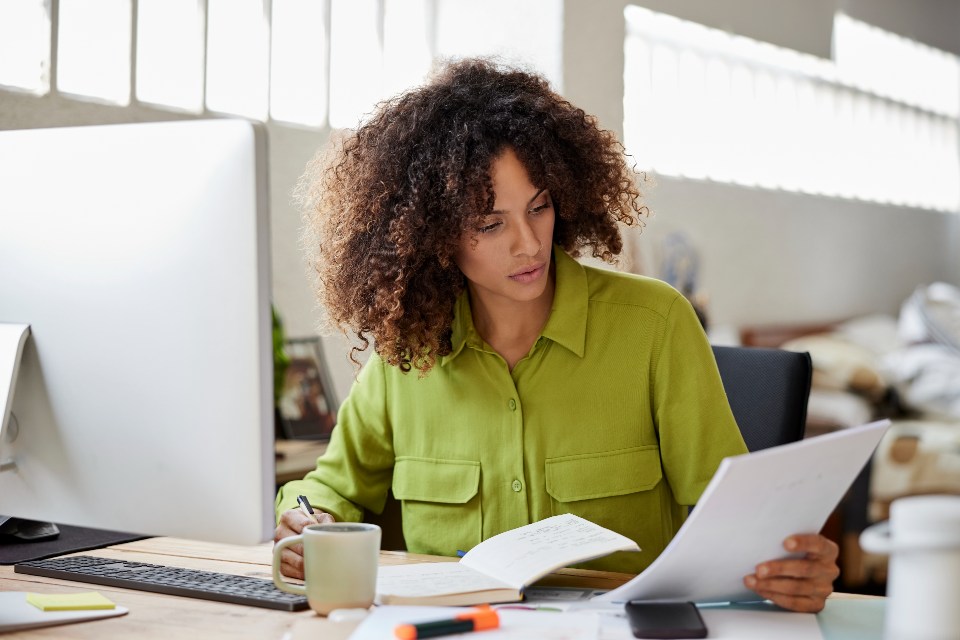 Woman at desk with computer looking at papers