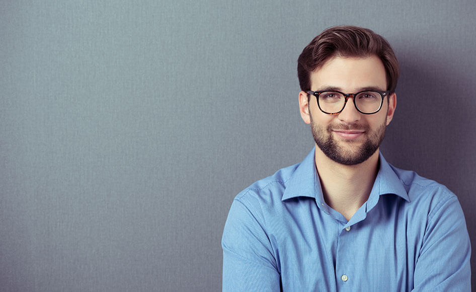 Young male student in glasses against grey background